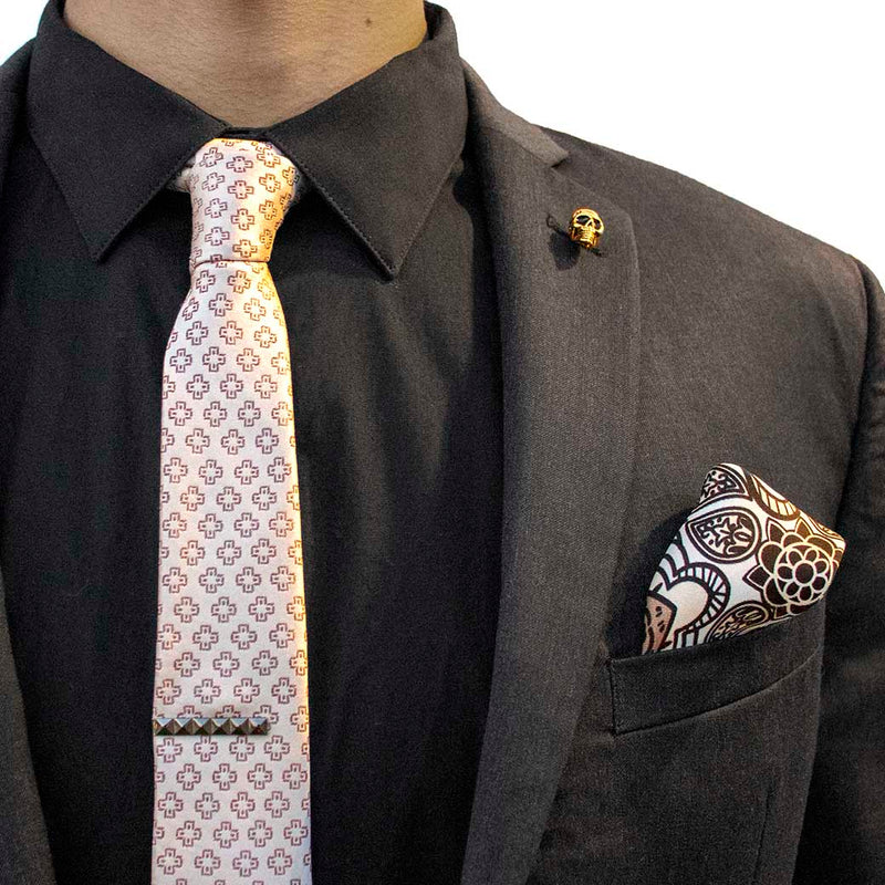 front angle of black charcoal suit with pharaoh set of men's suit accessories - he silk tie’s simple pattern resembling hieroglyphics is a great contrast to the ornamental, paisley silk pocket square, and the black tie bar resembling a sarcophagus is the perfect complement to the gold skull lapel pin of the pharaoh himself