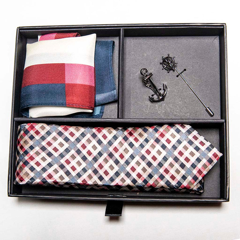 top view of voyage set of men's suit accessories in a gift box - The silver helm lapel pin on the breast represents choice, while the anchor tie bar on the chest symbolizes strength. These two coupled with the versatile, multi-colored silk tie and silk pocket square make a great combination 